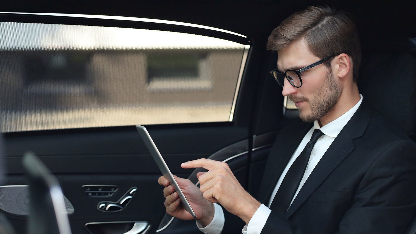 Person in the backseat of a luxury vehicle being driven.